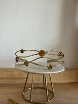 Gargantilla rígida de diseño abierto, confeccionada artesanalmente en bronce, con estructura de líneas onduladas entrelazadas y engarces circulares que contienen piedras naturales en tonos ámbar.