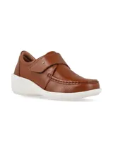 Zapato tipo slip on color camel, confeccionado en cuero con textura granulada. Presenta un diseño de mocasín con costuras reforzadas en la puntera, ajuste mediante una solapa con velcro y una suela de plataforma blanca de goma.