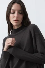 Polera de tejido de punto color gris oscuro, con cuello alto y diseño de rombos en relieve en el frente. Presenta un calce relajado con terminaciones en rib en cuello, puños y ruedo.