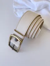 Cinto de cuero color crudo con hebilla rectangular de metal color bronce envejecido.