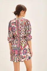 Vestido corto de cuello redondo con escote en V, mangas 3/4 con puños elásticos y lazo ajustable en la cintura. Presenta un estampado multicolor con motivos geométricos y florales.