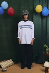 Remera de manga larga en color blanco, con cuello redondo y diseño de franjas horizontales en azul y verde en la parte superior del pecho, junto con el logo de la marca.