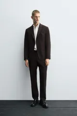 Blazer de corte regular confeccionado en tejido con lana, color marrón oscuro. Presenta cuello con solapas de muesca, cierre frontal de un botón, bolsillos con solapa en la cadera y bolsillo de vivo en el pecho.