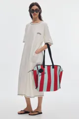 Tote bag de canvas con rayas verticales en rojo y celeste, asas negras, cierre superior y ribetes negros.