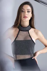 Vestido corto negro ajustado, con escote halter y detalles de strass plateados en la parte superior.