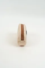 Neceser acolchado color beige con diseño de carita feliz bordada en el frente y cierre superior con tirador de cordón.