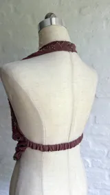 Top halter color marrón con escote pronunciado y detalle de frunce en el centro. La prenda está adornada con lentejuelas y cuentas bordadas en tonos cobrizos y rosados.