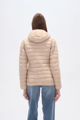 Campera acolchada tipo puffer, color beige claro, con capucha y cierre frontal. Presenta costuras horizontales y un calce entallado.