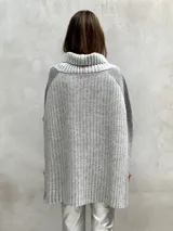 Poncho de lana gris con cuello alto y diseño de rayas verticales en dos tonos de gris.