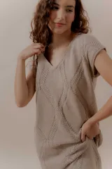 Vestido largo tejido color beige, con diseño en bloques de rombos, escote en V y flecos en el ruedo.