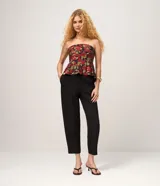 Pantalón carrot en crepé negro, de cintura alta, corte holgado en las caderas que se estrecha hacia los tobillos, con bolsillos laterales.