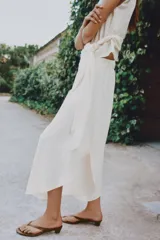 Pantalón fluido de tiro alto en color blanco, con pinzas delanteras, cintura elástica en la espalda y perneras anchas con aberturas laterales pronunciadas.