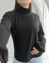 Polera negra de tejido de punto con cuello alto y mangas largas.