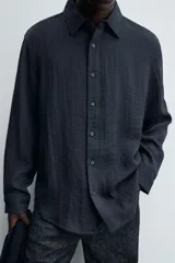Camisa de corte relajado confeccionada en tejido fluido con mezcla de viscosa. Presenta cuello solapa, cierre frontal con botones y manga larga con puños abotonados.