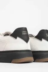 Zapatillas urbanas blancas con detalle azul en el talón y suela de goma.