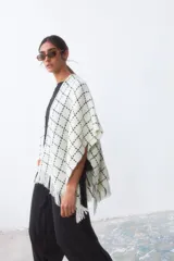 Ruana de tejido de punto con diseño a cuadros en color blanco y negro, con terminación de flecos en el ruedo.