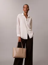 Cartera tote de Calvin Klein en color beige, con estampado de monograma CK repetido en toda la superficie, doble asa fija y diseño estructurado.
