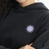 Canguro con capucha color blanco, de corte holgado y diseño básico. Presenta un bolsillo frontal tipo canguro y un pequeño estampado de sol con el logo de la marca en el pecho.