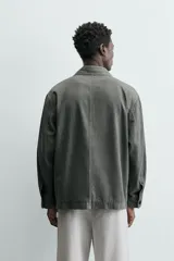 Sobrecamisa de hombre, color verde militar, con cuello solapa, manga larga y cierre frontal de botonadura. Presenta un bolsillo de plastrón en el pecho y bolsillos laterales en la cadera. El tejido tiene un efecto lavado.