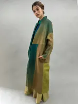 Tapado largo de lana merino afieltrada con diseño de paneles en degradé de tonos verdes y ocres. Presenta hombros caídos, mangas rectas, bolsillos laterales y cierre frontal con broches ocultos.