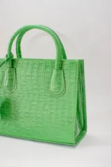 Cartera mediana de cuero blanco, con asa fija y correa regulable desmontable.