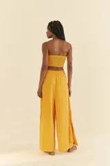 Pantalón amarillo de lino y viscosa, de pierna ancha, con cintura alta, pretina recta en la parte delantera y elástica en la parte trasera. Presenta detalle de trenza vertical en los laterales y aberturas en el dobladillo.