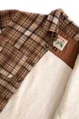 Camisa leñadora marrón a cuadros con forro de corderito sintético, cierre con botones y dos bolsillos frontales con tapa.