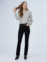 Camisa de manga larga, color blanco y negro, con cuello con solapa y abertura central con botones ocultos. Presenta un estampado geométrico repetitivo.