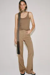 Pantalón flare de tiro medio, confeccionado en mezcla de viscosa y lino, con diseño de rayas verticales en tono beige. Cuenta con bolsillos delanteros y bajo acabado en línea evasé. Cierre frontal con cremallera, botón y ganchos metálicos.