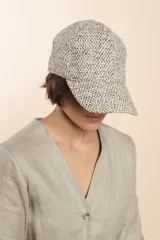 Gorra con visera confeccionada en lana fina sin teñir, con un sutil patrón de tejido en espiga.