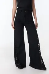 Pantalón de jean azul oscuro de pierna ancha y tiro medio, con paneles laterales en contraste de color marrón. Presenta costuras pespunteadas en tono tostado y terminación desmechada en el bajo.