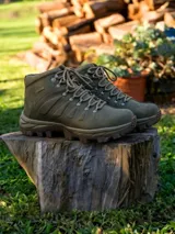 Botín de trekking color verde oliva, con diseño de caña media, cordones reforzados y suela de goma con relieve para mayor tracción.