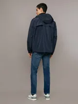 Campera ligera Calvin Klein de corte regular, confeccionada en tejido técnico resistente al viento. Presenta capucha con cordones ajustables, cierre frontal con cremallera, bolsillos laterales con cierre y puños elásticos.