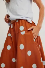 Falda midi de corte A y cintura baja, confeccionada en popelina de algodón color marrón terracota con estampado de lunares celestes.