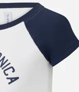 Remera de estilo college con cuerpo blanco y mangas raglán cortas en color azul marino. Presenta cuello redondo y estampa frontal con diseño gráfico deportivo de Santa Monica.