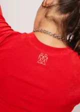 Remera roja de tela stretch suave con leve brillo y mangas cortas. Tiene el isotipo de la marca bordado en la espalda.