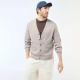 Cárdigan de punto color beige con cuello en V, cierre frontal con botones y dos bolsillos delanteros. Presenta puños y ruedo acanalados.