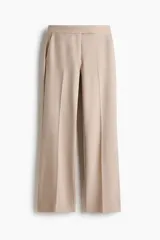 Pantalón de vestir de corte acampanado, color beige, con pretina, cierre frontal, bolsillos laterales y pliegues frontales.