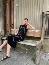 Vestido midi negro con estampado de líneas blancas, sin mangas y cuello redondo.