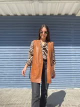 Chaleco largo de cuero color óxido, con bolsillos frontales y aberturas laterales ajustables con tiras.