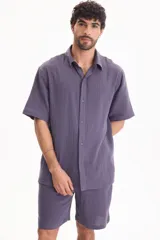 Camisa de muselina de manga corta color beige, con cuello camisero y cierre frontal de botones.