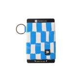 Billetera elástica de diseño compacto con estampado de bloques en tonos azul y blanco. Cuenta con una argolla metálica lateral para enganchar llaves y una pequeña etiqueta con el logo de la marca.