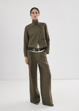 Chaqueta corta de lino color verde militar, de corte recto, con cuello alto camisero y cierre de doble botonadura.