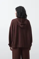 Campera con capucha y cierre frontal, de silueta relajada, hombros caídos y bolsillos laterales. Presenta terminaciones elastizadas en puños y ruedo, con líneas de recorte frontales y cierre metálico con tirador circular.