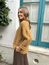 Sweater de tejido de punto color beige, con cuello redondo, mangas largas con puños doblados y diseño holgado.