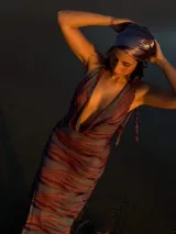 Vestido largo de silueta ajustada, con estampado abstracto en tonos azules, morados y naranjas. Presenta un escote drapeado profundo y tirantes finos.