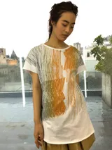 Remera blanca de algodón con estampado abstracto en tonos ocre, verde y gris. De corte holgado y mangas cortas.