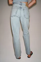 Pantalón de jean de tiro bajo y corte recto, con diseño de cinco bolsillos y cierre frontal con cremallera y botón metálico. Presenta un lavado claro.