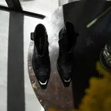 Botín de cuero vacuno color marrón oscuro, con taco de madera foliado en cuero de 5cm de altura, cierre lateral interno y horma de punta fina.