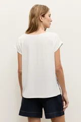 Blusa de manga corta color crudo con estampado de lunares negros y escote en V.